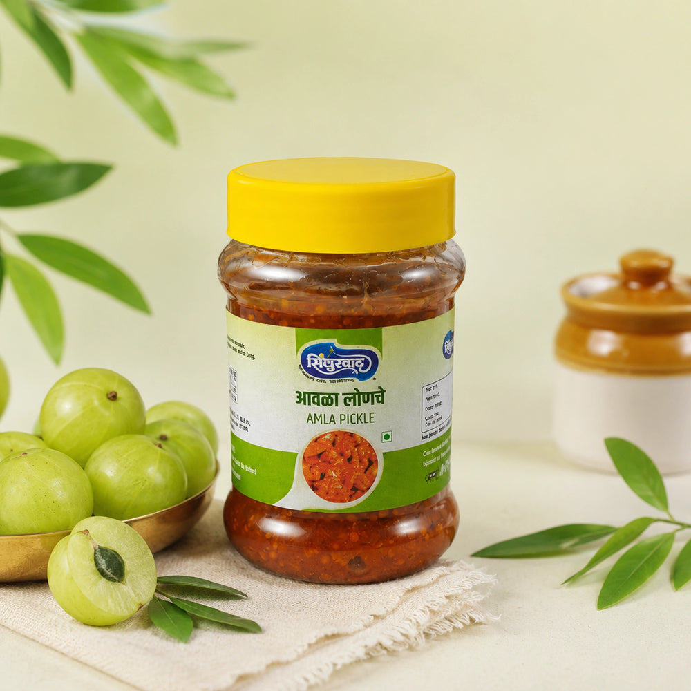 A jar of Amila Redde (amaranthum) spread by Shiv Kumar, featuring a bright yellow lid and a green and white label, styled with green amlas and leaves on a light beige surface.