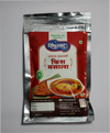 A close-up of premium reddish-brown Sindhuswad Malwani fish curry masala powder in a traditional rustic bowl