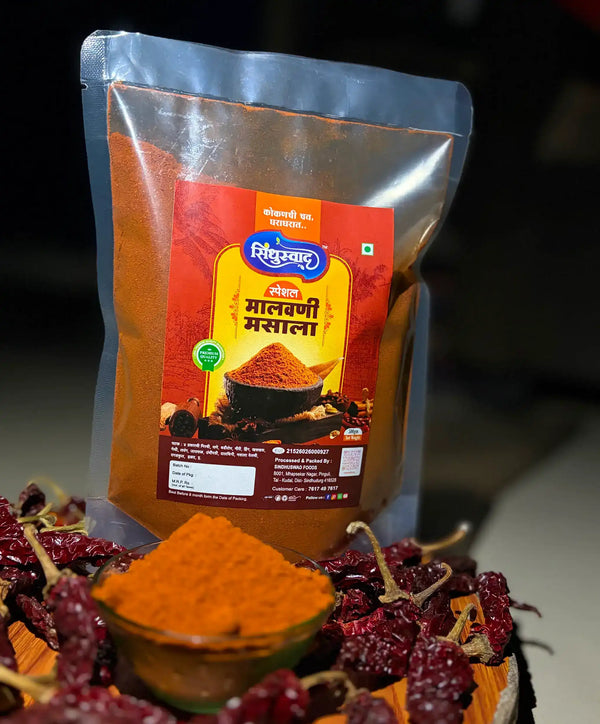 A close-up shot of vibrant reddish-brown traditional Sindhuswad Malvani masala powder in a small rustic bowl.